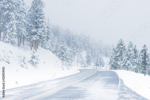 Beautiful winter scene with icy slick road driving situation curving road covered with snow and snowy trees all around © Condor 36