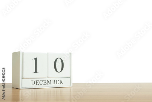 Closeup surface white wooden calendar with black 10 december word on blurred brown wood desk isolated on white background with copy space , selective focus at the calendar