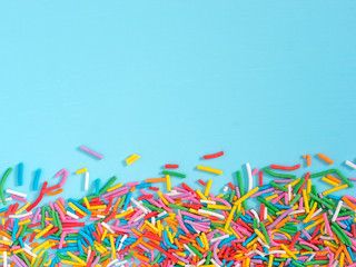 Border frame of colorful sprinkles on blue background