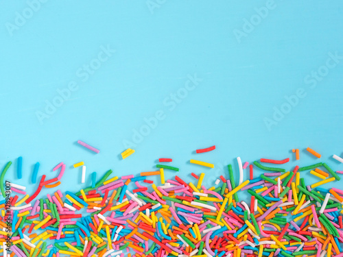 Border frame of colorful sprinkles on blue background
