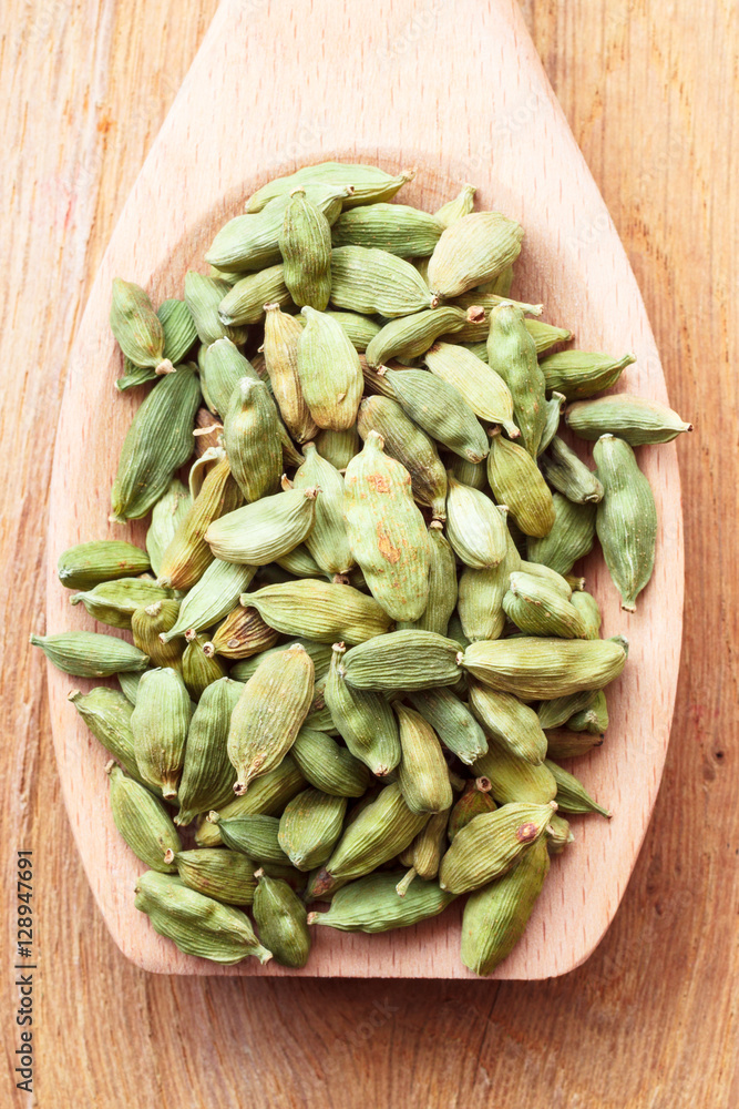 Green cardamom pods on wooden spoon Green cardamom pods on wooden spoon