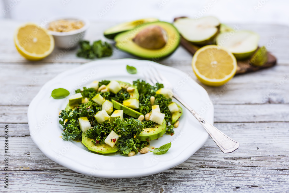 Fresh salad with kale leaves and avocado with pear on a white plate on wooden table. Fresh salad with kale leaves and avocado with pear on a white plate on wooden table.