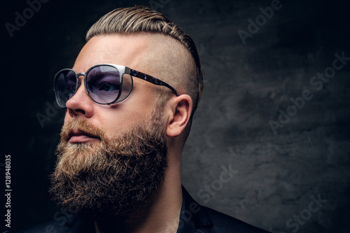 A bearded man in purple sunglasses isolated on grey vignette bac