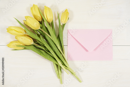 Bouquet of fresh tulips and envelope beside