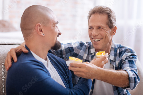 Smiling non-traditional couple feeding each other with cupcakes