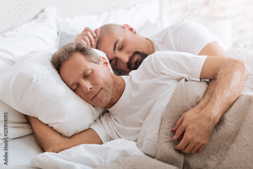 Positive delighted non-traditional couple sleeping together