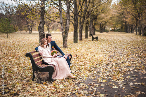 The beautiful bride and handsome groom sitting on a bench in the © nagaets