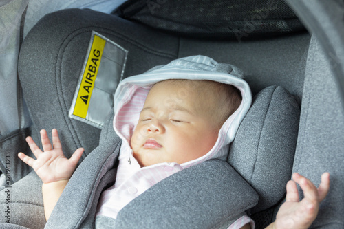 Asian cute newborn baby sleeping in modern car seat.