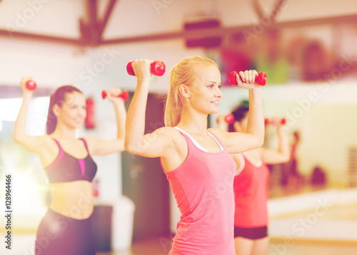 group of smiling women working out with dumbbells