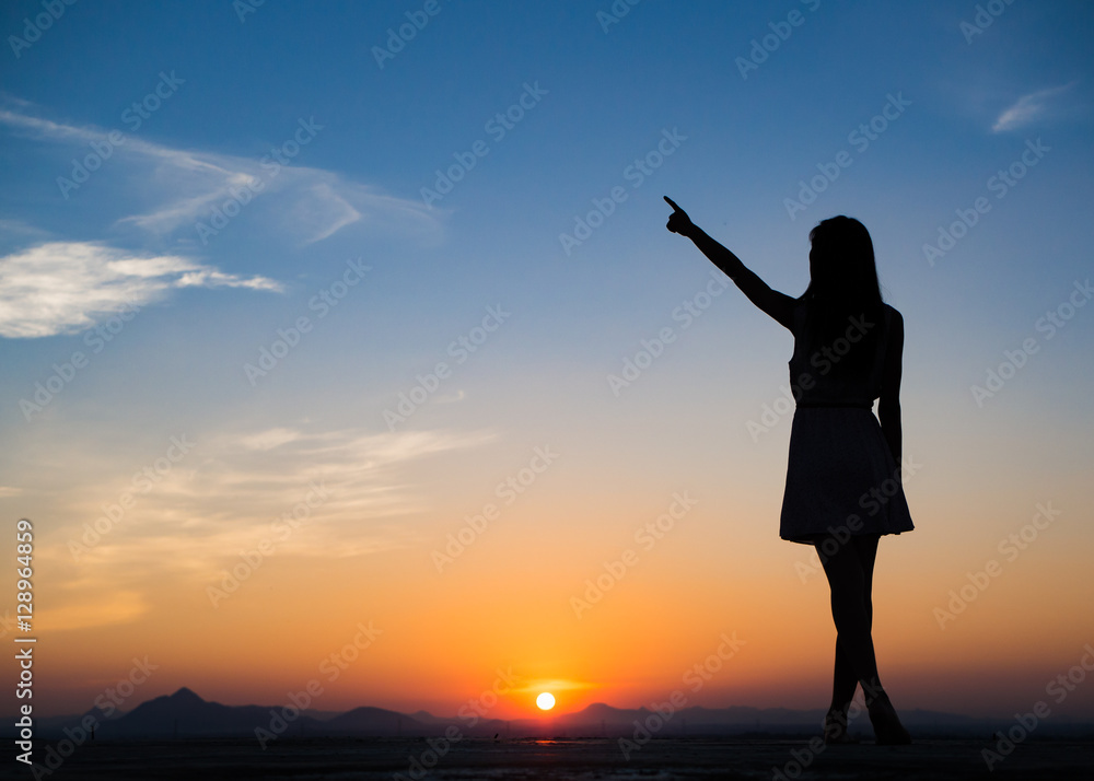 Fototapeta premium Silhouette of free woman enjoying freedom feeling happy at sunset. Serene relaxing woman in pure happiness