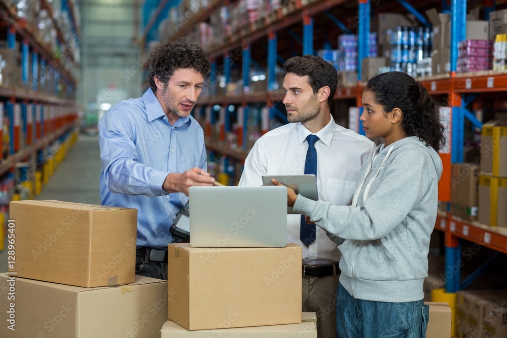 Warehouse manager and worker discussing with laptop Warehouse manager and worker discussing with laptop
