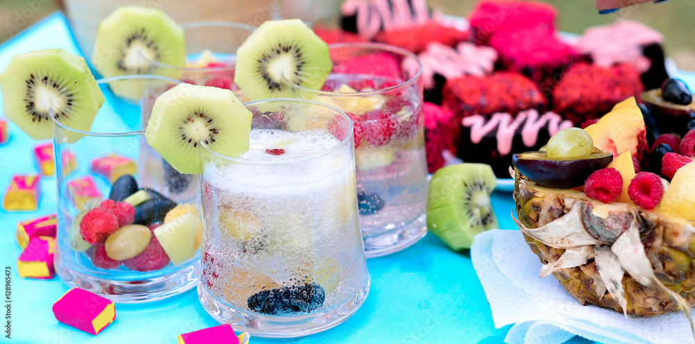 Champagne with fruit in a beautiful glass. Colorful Cakes on the occasion. Picnic table.
