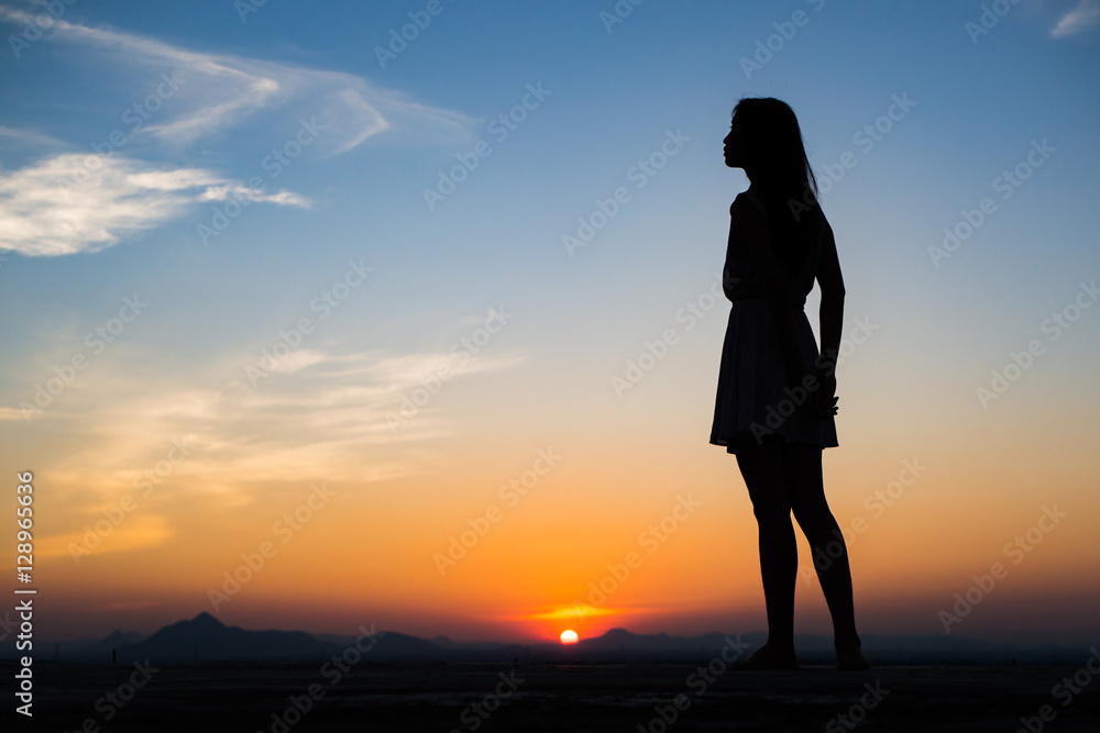 Fototapeta premium Silhouette of free woman enjoying freedom feeling happy at sunset. Serene relaxing woman in pure happiness