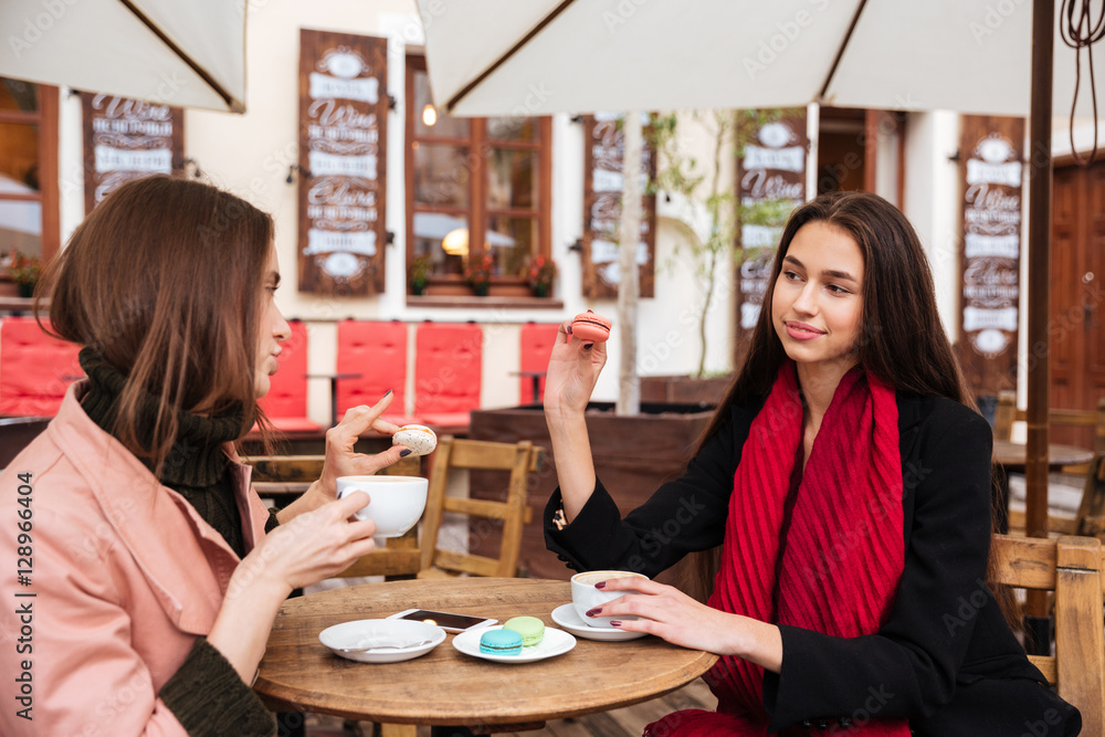 Two women drinking coffe with french macaroons in outdoor cafe Two women drinking coffe with french macaroons in outdoor cafe