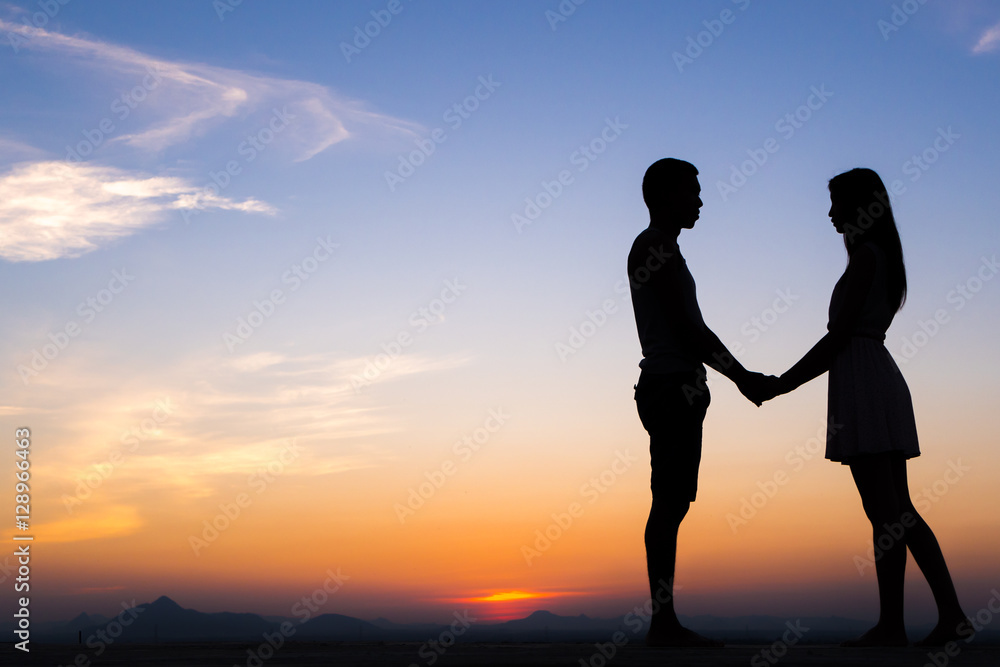 Silhouette of Happy Young Couple Hugging Outside at Sunset,proposing