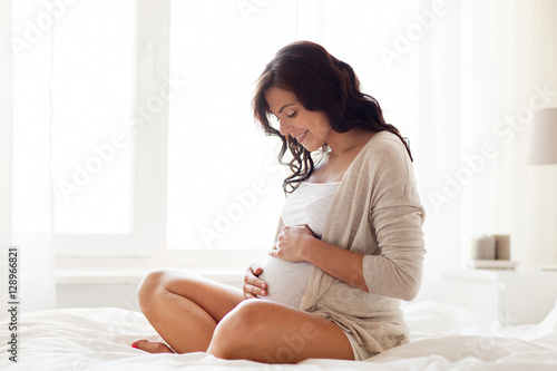 Fotografia happy pregnant woman sitting on bed at home