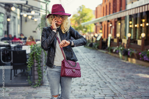 Hipster woman looking at her smartwatch and talking on cellphone photo