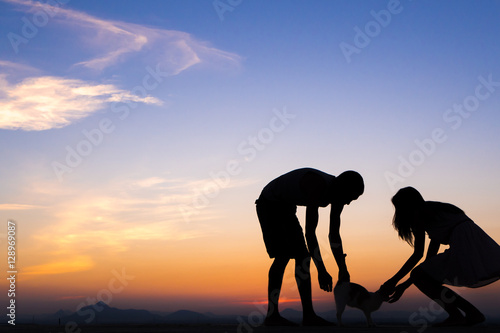 Silhouette of Happy Young Couple playing with cat Outside at Sunset © max_play