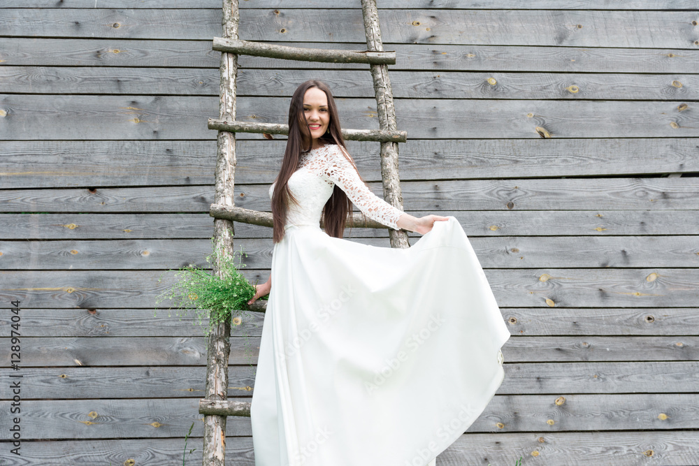 Fototapeta premium Bride in nature, a wooden warehouse in the background