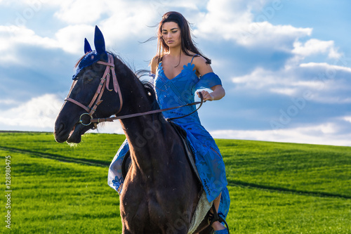 beautiful young woman riding a horse in a meadow