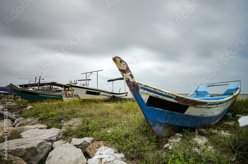 closed up fisherman boat stranded on the sandy beach and cloudy sky.color toning applied.color toning applied