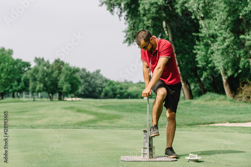 Greenskeeper cutting a golf hole