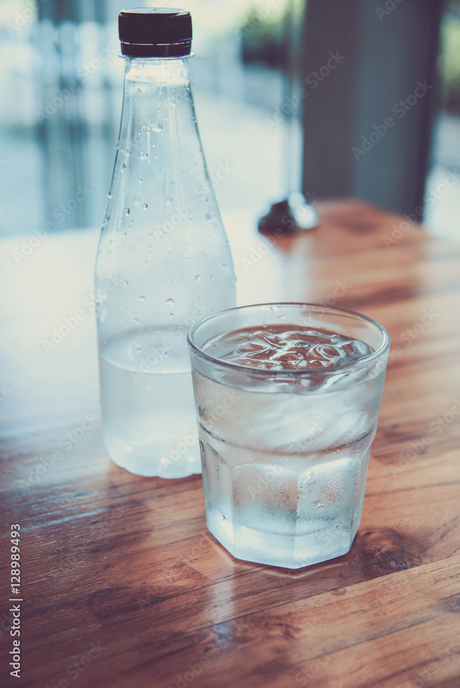 Glasses with ice cubes and water bottles on wooden table Glasses with ice cubes and water bottles on wooden table
