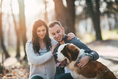People and dogs. Young couple enjoying nature or park outdoors together with their  adorable Saint Bernard puppy. photo