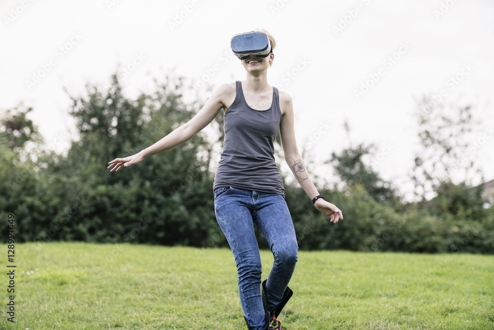 Smiling young woman using Virtual Reality Glasses outdoors