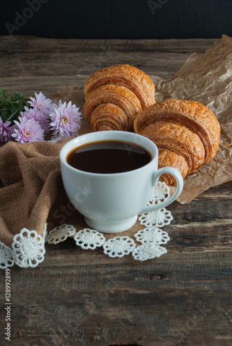 Breakfast. Coffee and croissants. Dark wood background. Vertical