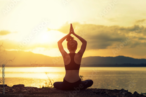 Young healthy woman practicing yoga on the beach at sunset © weerasak