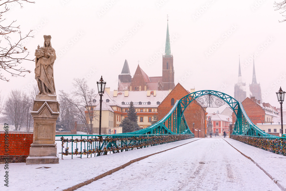 Obraz premium Tumski Bridge and Island with Cathedral of St. John and church of the Holy Cross and St. Bartholomew in the snowy overcast winter day in Wroclaw, Poland