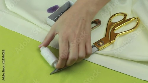 Tailor Removes Sewing Utensils With a Piece of Fabric - a Pair of Scissors, Tailor's Cutter, Thread, Dressmaker Pins, Chalk and a Needle and Thread.