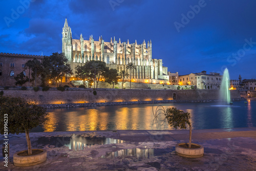 Illuminated Cathedral of Palma de Mallorca seen from Parc de Mar after a heavy rain shower