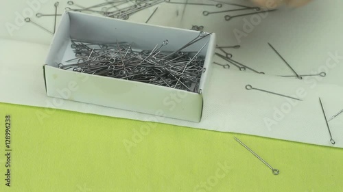 Tailor Puts Dressmaker Pins Into the Box, Which Were Scattered on a Beige Fabric 2