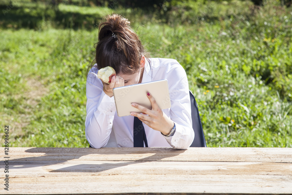 Fototapeta premium depressed business woman eating an apple and reading messages