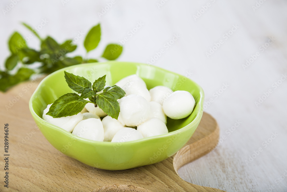 Mozzarella in a green plate on a wooden table. Delicious fresh c