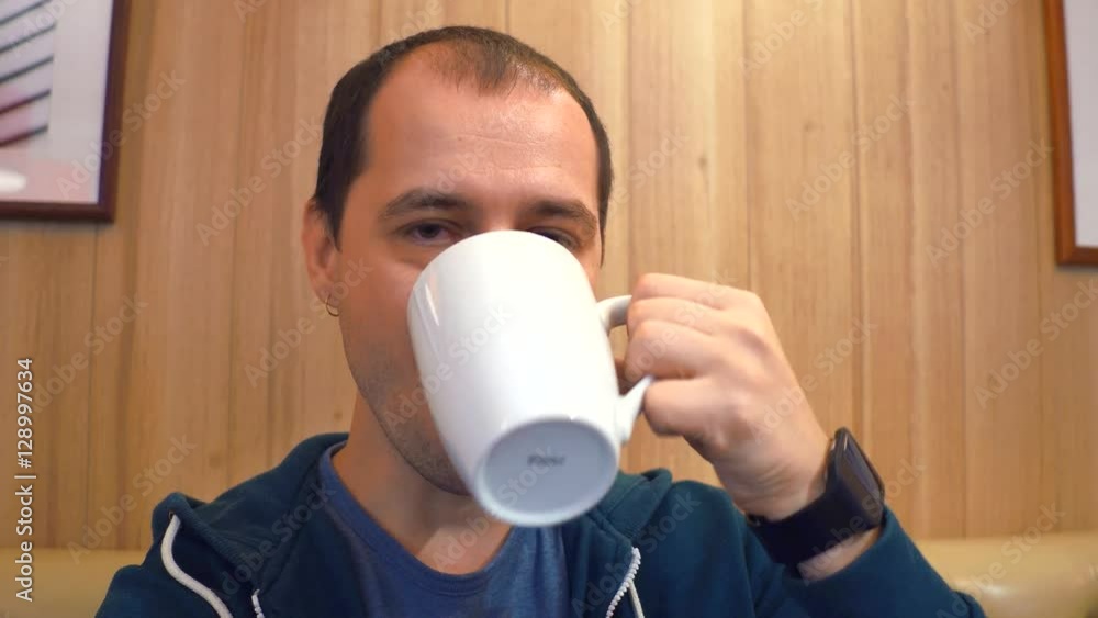 Serious young man having big cup of coffee to keep him awake in a cafe. 4K shot Serious young man having big cup of coffee to keep him awake in a cafe. 4K shot