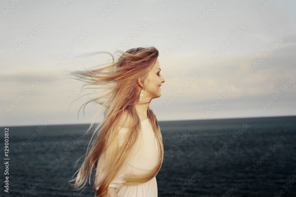 Obraz premium Beautiful blond woman in white dress enjoying the sea wind. Freedom to travel, enjoy nature, happiness