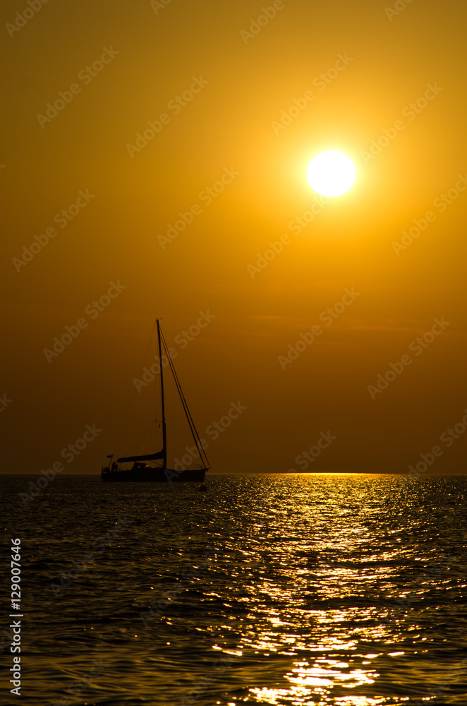 Silhouette of a yacht on a sea surface at sunset in Greece