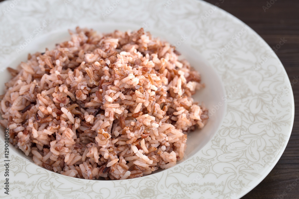 Ripe purple Rice berry in the dish on dark brown wooden plate Ripe purple Rice berry in the dish on dark brown wooden plate