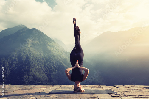 Fotografia Young woman doing complex Yoga exercise headstand with Namaste asana