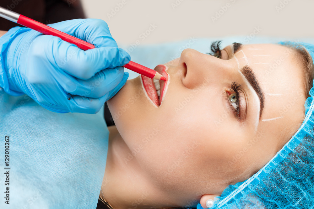 Naklejka premium Cosmetologist making permanent makeup on woman's face
