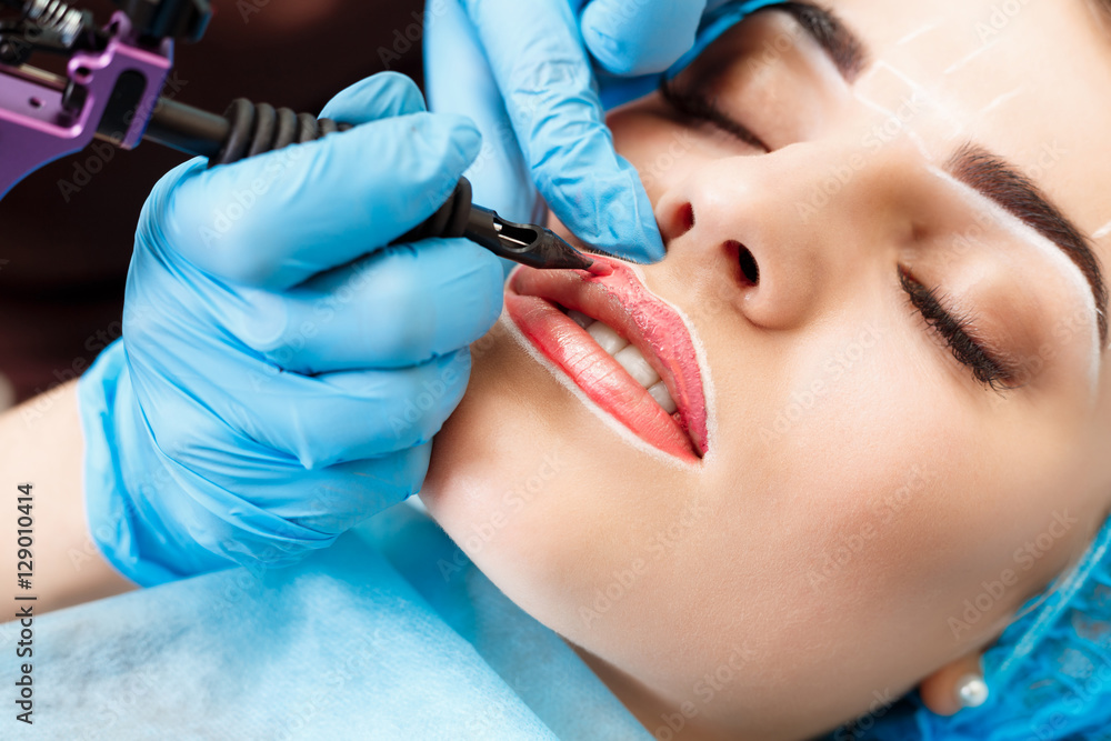 Naklejka premium Cosmetologist making permanent makeup on woman's face