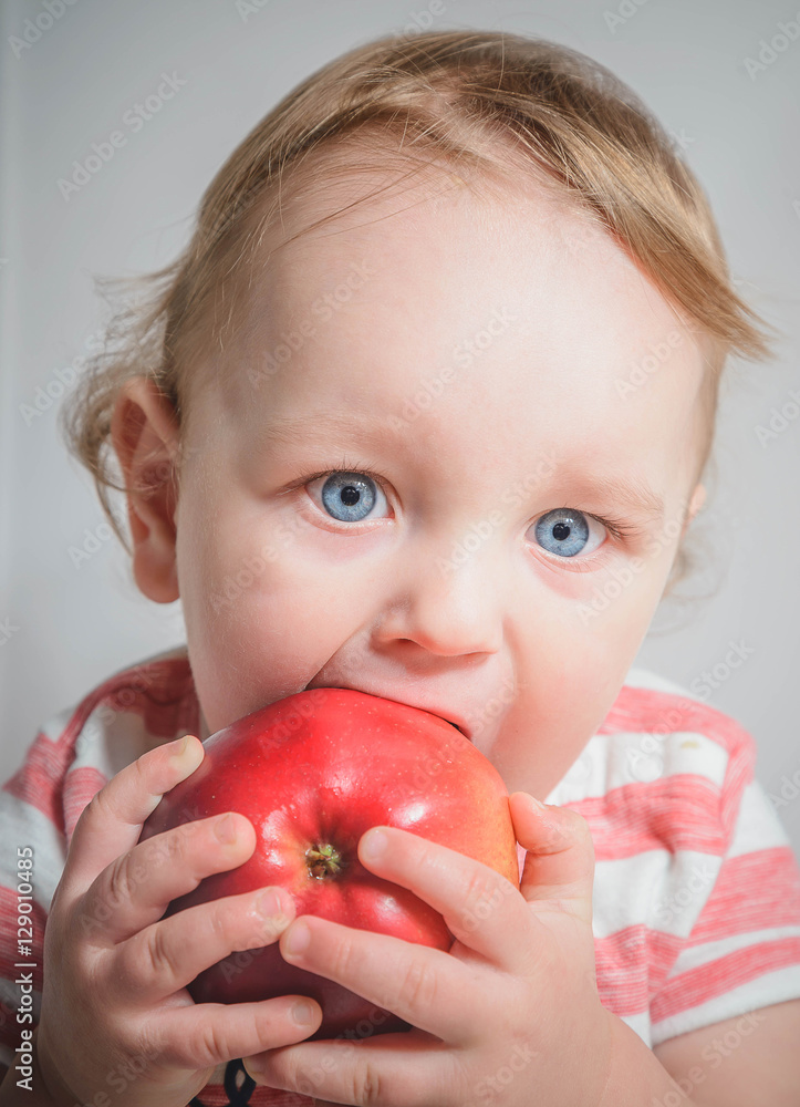 The child holds and eats an apple The child holds and eats an apple