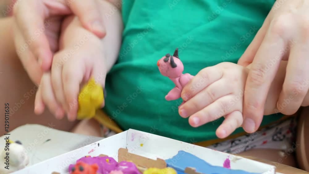Beautiful baby boy sculpts the clay with his mother at home. Together having fun and making animal figurines. child education concept Beautiful baby boy sculpts the clay with his mother at home. Together having fun and making animal figurines. child education concept