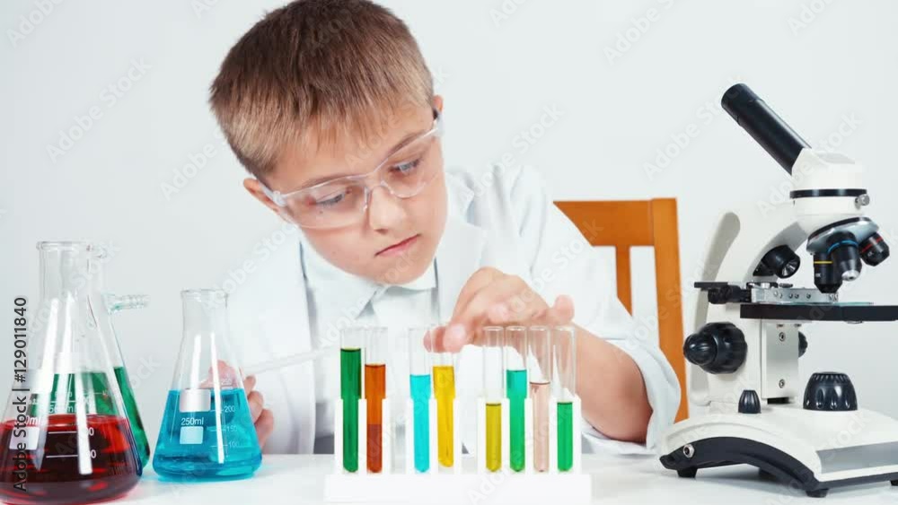 Close up portrait young chemist schoolboy looking at test tube with chemicals liquids Close up portrait young chemist schoolboy looking at test tube with chemicals liquids