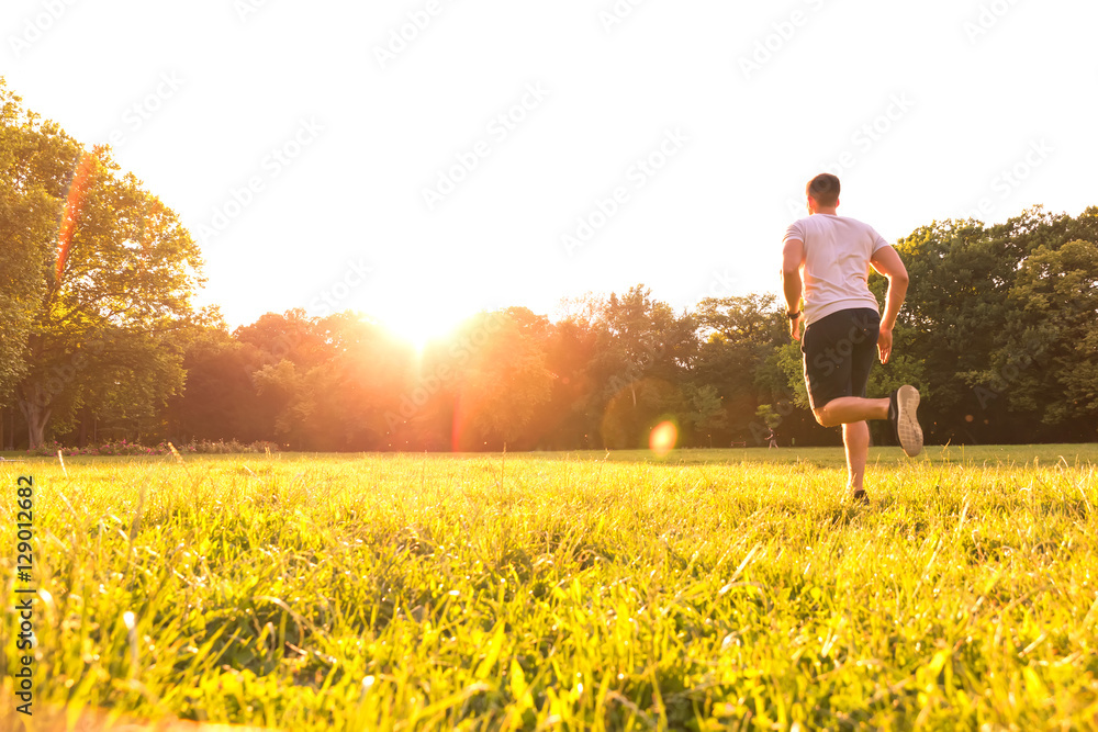 A handsome young man running during sunset in a park A handsome young man running during sunset in a park