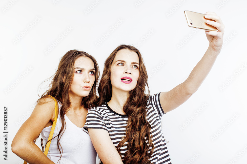Positive young woman hold phone in hand and take selfie. She pose on phone  camera in white office. Blurred background Stock Photo | Adobe Stock