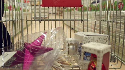 Girl is buying christmas goods in shop, she puts the christmas decorations to the shopping cart, timelaps
 photo